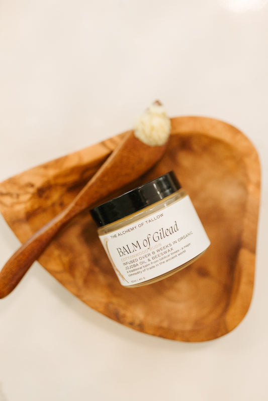 Jar of Balm of Gilead on a wooden tray with a wooden applicator.