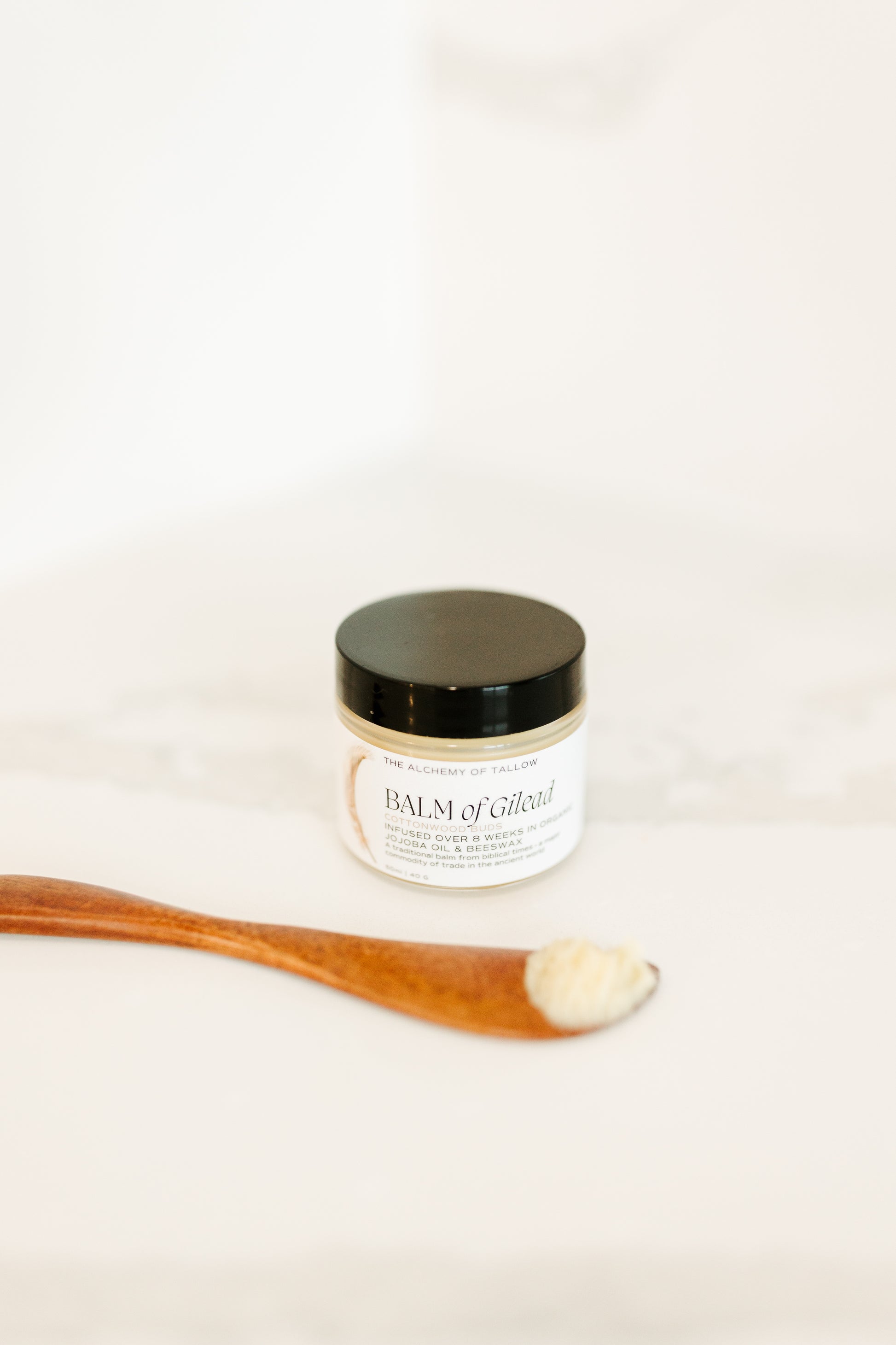 Jar of Balm of Gilead with wooden applicator on a white background