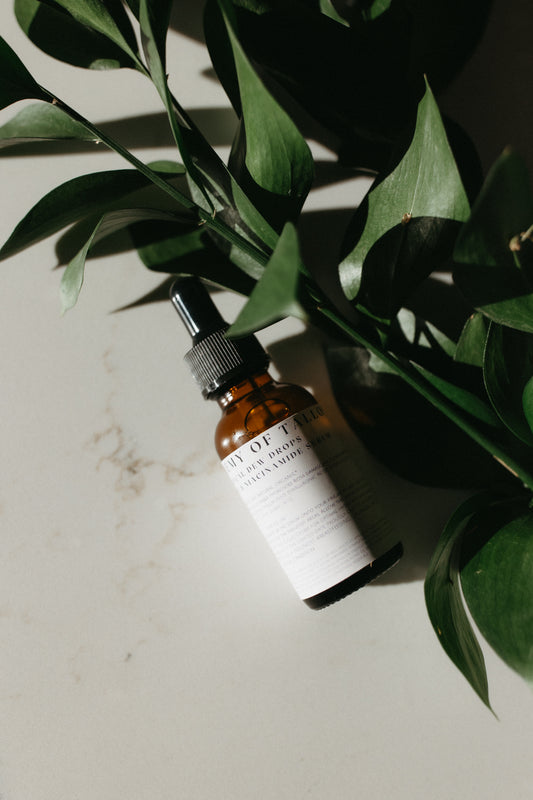 30ml bottle of Botanical Dew Drops serum, displayed alongside botanical elements, highlighting its hydrating formula with niacinamide and hyaluronic acid, designed to refine skin texture and provide deep hydration for a radiant complexion.