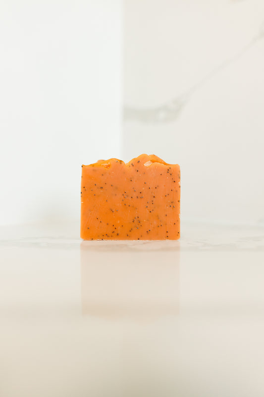 Orange soap bar with specks on a white background