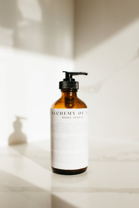Amber glass jar labeled “Cera Alba Body Serum” surrounded by beeswax, mango butter, and botanical elements, showcasing a rich, handcrafted body moisturizer designed to nourish and protect the skin. Organic mango butter, organic castor oil, beeswax, cera alba, body serum, rice bran oil, organic jojoba oil 